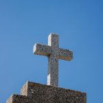 Simple stone cross on a structure with clear blue sky backdrop in Santa Marta, Colombia.